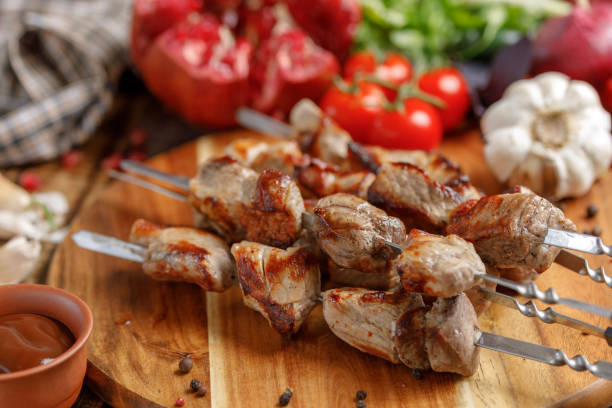 istock Juicy appetizing shish kebabs cooked on an open fire. Still life with textiles on a wooden background. 954220834