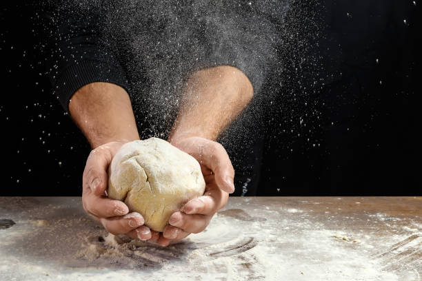 close-up de chef masculino mãos, sove a massa, cozinhe a massa em um fundo escuro. - bread kneading making human hand - fotografias e filmes do acervo