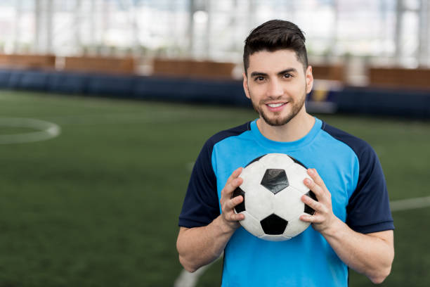 istock Young soccer player looking at camera smiling with confidence while holding a soccer ball 954226680