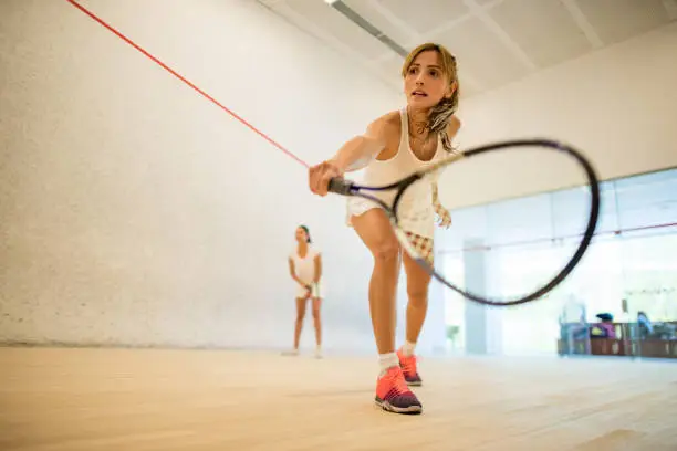 Young beautiful women playing squash at the club