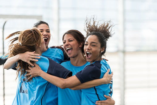 Excited female soccer players hugging after scoring a goal very happy