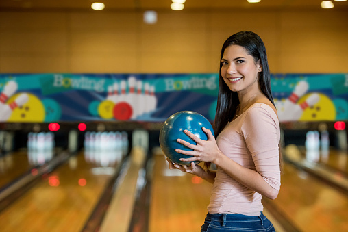 Gorgeous latin american woman at the bowling alley ready to play looking at camera smiling very happy