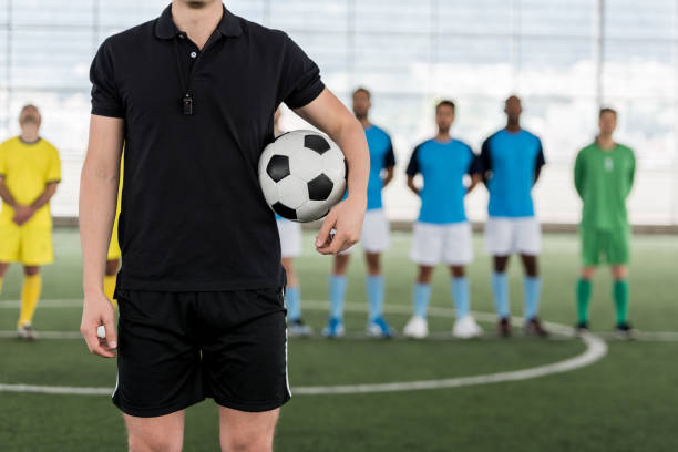 istock Unrecognizable referee holding a soccer ball and team standing at the background 954226776