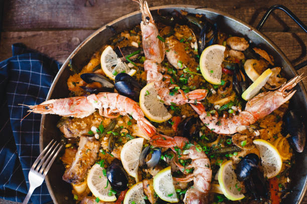 istock Fresh paella in pan on wooden table 954228978
