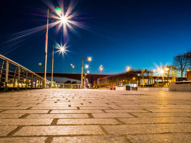 low level photographic view of pavement and city light at sunset with blue sky