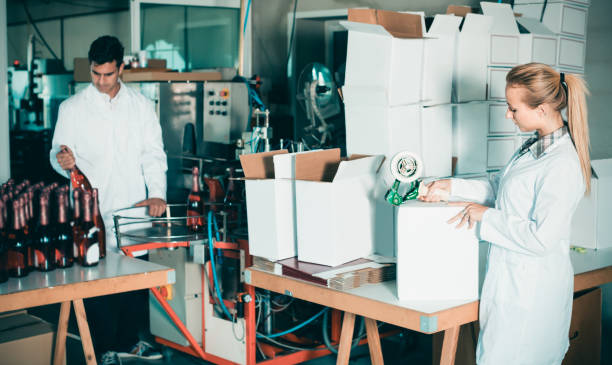 istock Young woman in uniform packing wine bottles 954230152