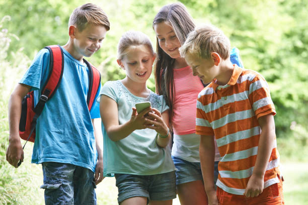 istock Group Of Children Geocaching Using Mobile Phone In Forest 954242328