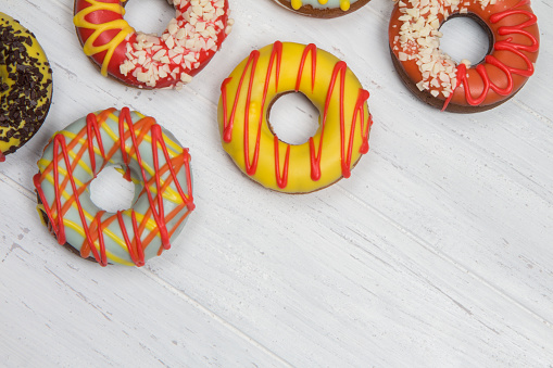 Colored donuts on wooden background. Candy bar on white table. Place for your text.