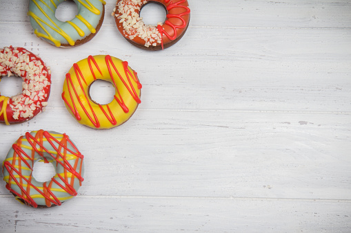 White wooden table with colorful sweet donuts. Space for your text. Darkening effect, vignette