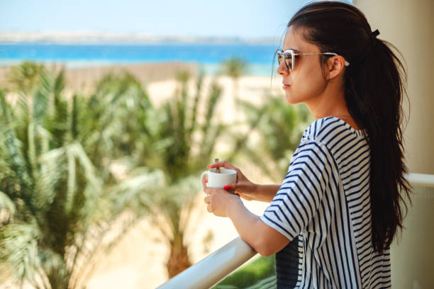 fille, appréciant la tasse de café sur un balcon - beach on child the photos et images de collection