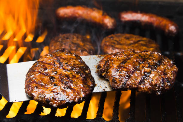 cuatro hamburguesas de carne de res y dos salchichas en una parrilla de barbacoa caliente - sausage bratwurst barbecue grill barbecue fotografías e imágenes de stock