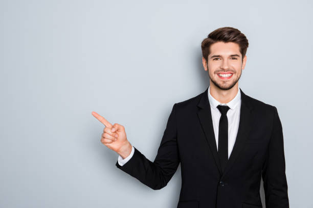 istock Handsome young businessman in black suit pointing with finger 954260400