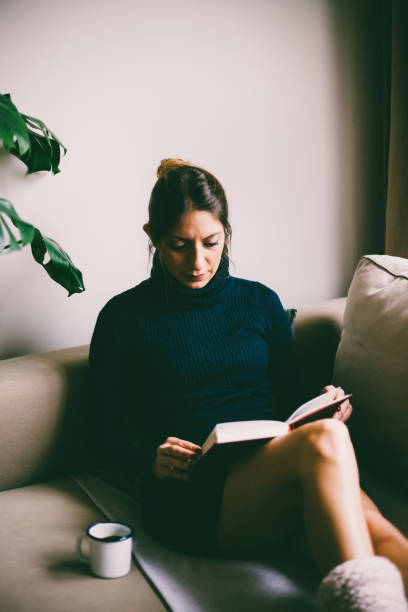istock Beautiful young woman reading a book and drinks coffee (toned image, selective focus) 954260652