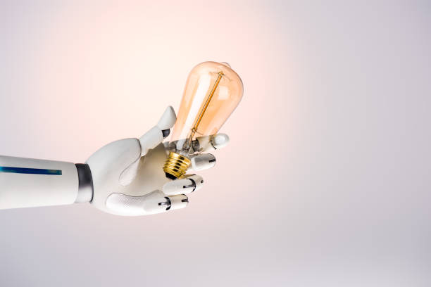 istock robot hand holding yellow lamp isolated on beige 954260714