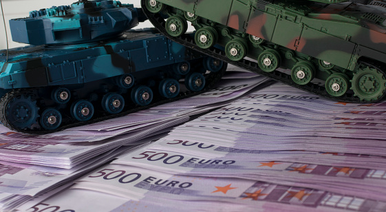 Close up green and blue tank toy placed on euro banknotes pile. business and economy war. new world war from business and economy concept. Concept of expense and cost of war