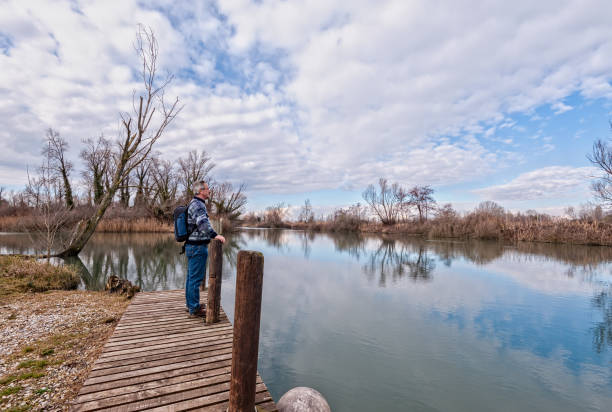 istock Hiker with backpack over wood pier on shore of river. 954265998