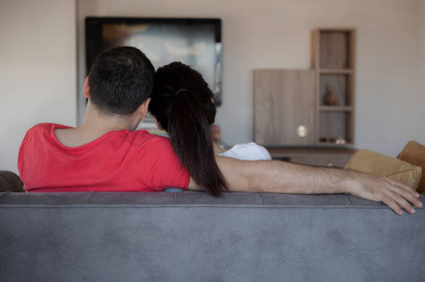istock Loving couple watching tv at home 954267002