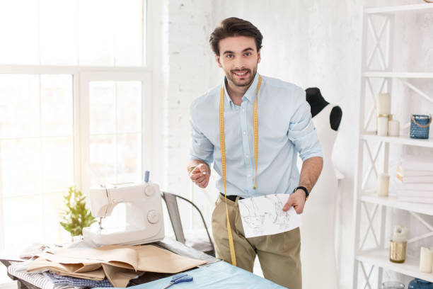 istock Happy professional dressmaker holding his sketches 954267540