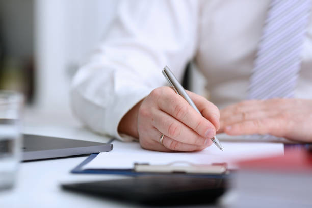 istock Male arm in suit and tie hold silver pen 954267612