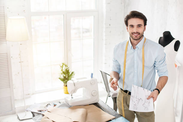 istock Smiling professional dressmaker holding his sketches 954267734