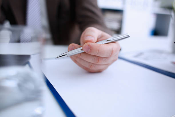 istock Male arm in suit and tie hold silver pen 954267740