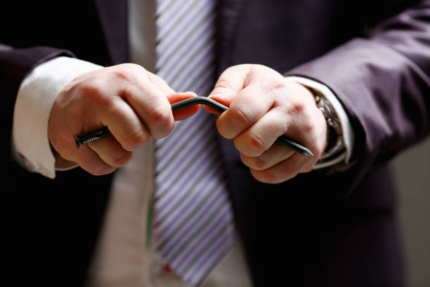 istock Man in suit and tie bend nail with arms closeup 954267840