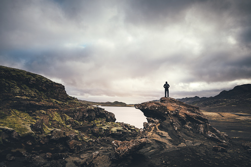 Man standing on the rock and enjoying the view on lake Kleifarvatn on the Reykjanes Peninsula in Iceland.