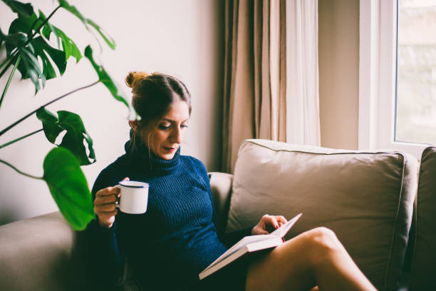 istock Beautiful young woman reading a book and drinks coffee (toned image, selective focus) 954270972
