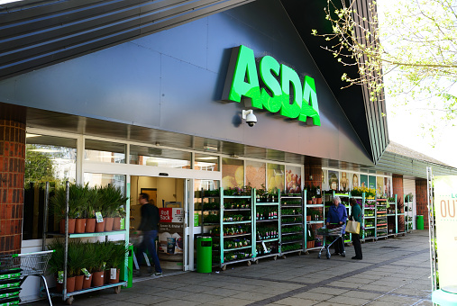 Waterlooville, UK - May 2, 2018: Asda Stores Ltd. trading as Asda, is a British supermarket retailer. The logo is prominent above the glass fronted store-front. \nAdvertising, products and Sshoppers are all visible.