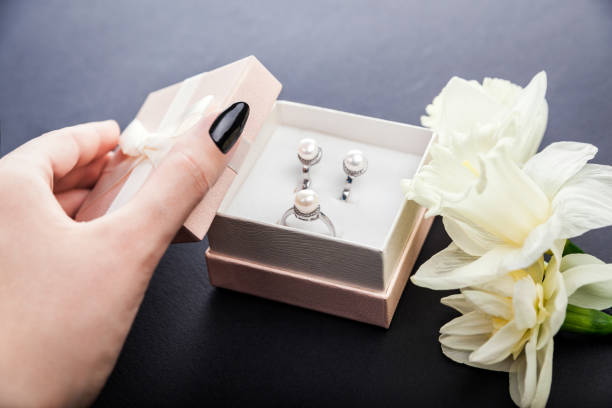 mulher abre a caixa de presente com joia da pérola. conjunto de brincos e anel com flores como um presente para o dia da mãe. - day gem ring open - fotografias e filmes do acervo