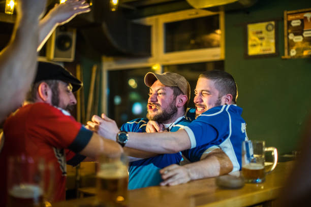 Men fighting in a pub Angry soccer fans of two rival  teams fighting in sports bar cross match stock pictures, royalty-free photos & images