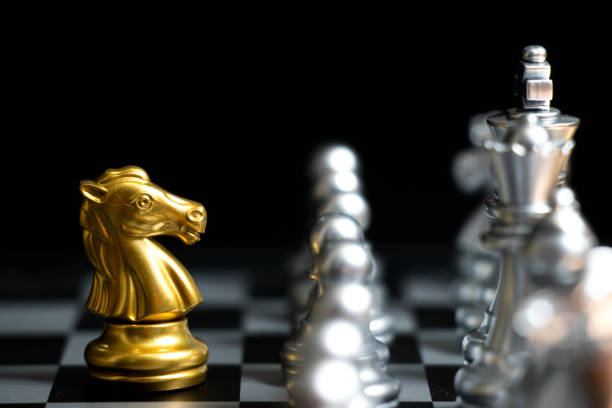 istock Gold horse in chess game face with the another silver team on black background (Concept for company strategy, business victory or decision) 954290118