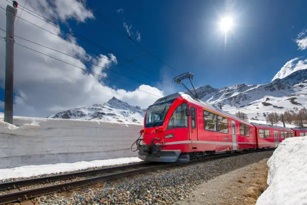 Swiss mountain train Bernina Express crossed Alps with snow wall.