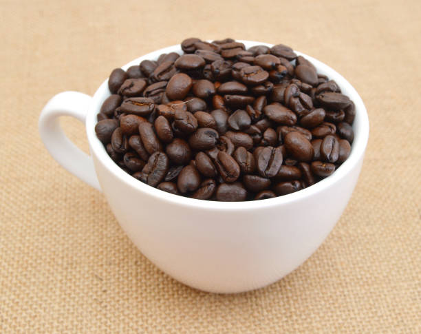 istock Cup and coffee beans on burlap background 954292162