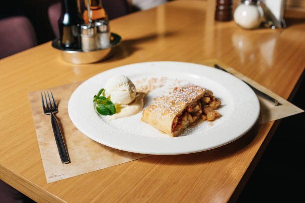 istock Fruit strudel and ice cream ball with Sabayon sauce a mint leaf on a white plate on a table in a restaurant. 954305868
