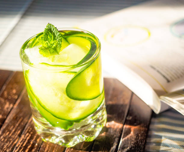 Refreshment drink with cucumber and mint leaves next to study book