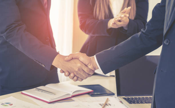 istock business man with low handshake with partner and woman cheering 954314668
