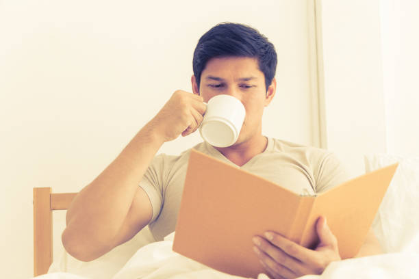 istock male is reading book and drink coffee on morning bed 954314932