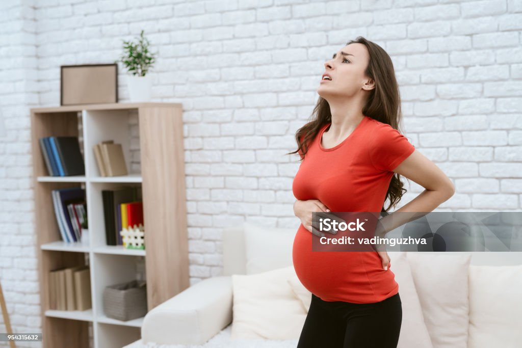 A pregnant girl feels pain. A pregnant girl feels pain. Her back hurts. She is at home. Pregnant Stock Photo