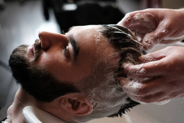Hairdresser man washes client's head in barbershop stock photo