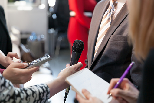 A female journalist with a microphone interviewing a businessman