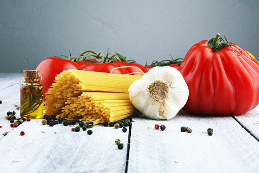 Italian food background with pasta, basil and tomato, health or vegetarian concept. Top view with copy space.