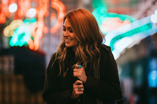 A beautiful and happy woman woman walks around downtown Seattle, exploring the city night life.  She is illuminated by the surrounding fluorescent lights.