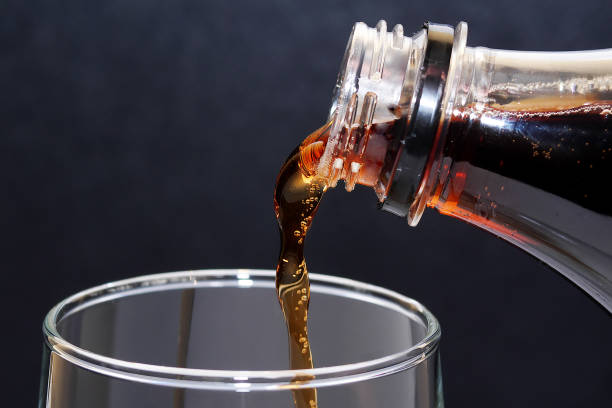 istock close up on cola being poured into glass against dark background 954334554
