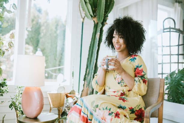 una mujer joven se relaja en su hogar moderno - floral dress fotografías e imágenes de stock