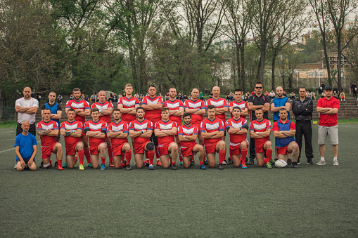 Group of people standing on the field, group photo of rugby team.