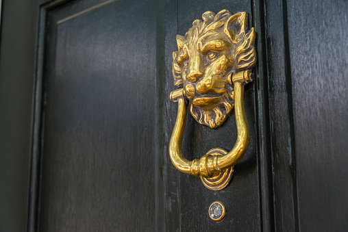 An old-fashioned door knocker in the shape of a lion on the front door of a historic house in the residential old town neighborhood of Charleston, South Carolina.
