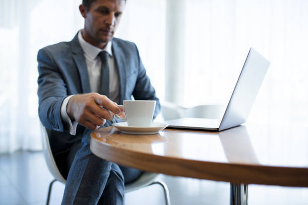 istock Businessman sitting at a table with laptop and coffee 954353580