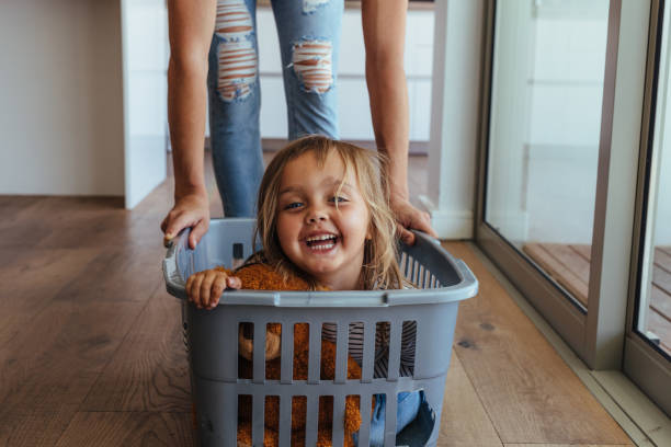 istock Little girl and her mother having fun doing laundry 954356902