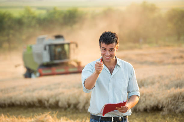 istock Engineer with note book and combine harvester in field 954358238
